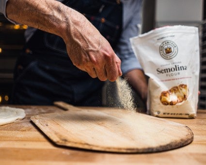 Baker adding semolina to a baking peel