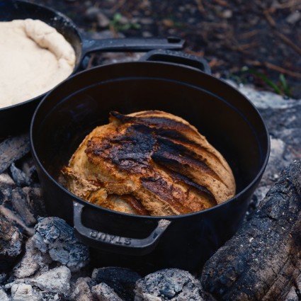 Sourdough being baked in a Dutch oven over a campfire 