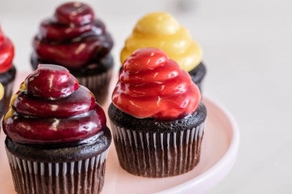 Cupcakes frosted with ermine buttercream frosting dipped in a variety of colors of mirror glaze