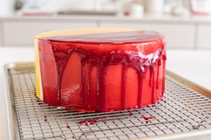 A cake coated in raspberry mirror glaze that was too cold when it was poured over a cake