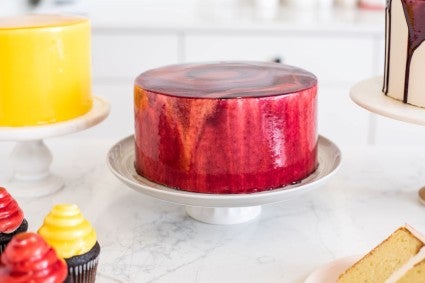 A tri-color tie dyed cake made with berry mirror glaze