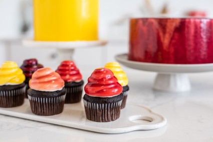 Cakes finished with a variety of flavors of mirror glaze and berry mirror-glazed cupcakes