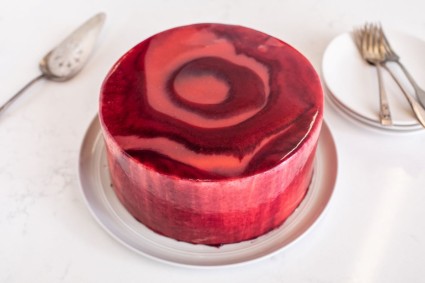 A cake finished with three kinds of berry mirror glaze: raspberry, blueberry, and strawberry mirror glaze