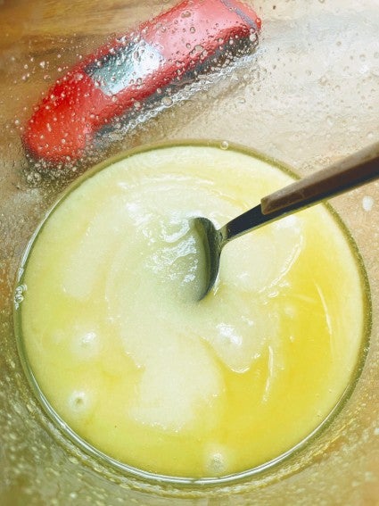 Butter and sugar melted together in a clear glass bowl, digital thermometer in the background.