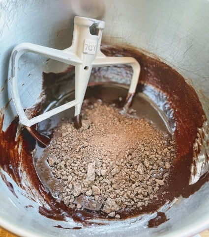 Brownie batter in a bowl, chopped semisweet chocolate on top ready to be blended in.