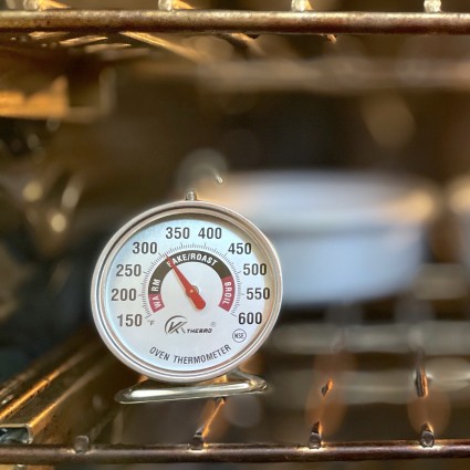 Oven thermometer in a 325°F oven, cake pans in the back.