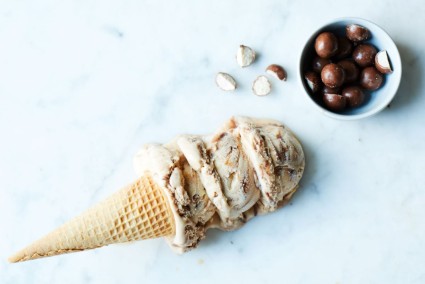 An ice cream cone next to a ball of chocolate malted milk balls
