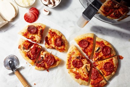 Two air fryer pizzas on a white tabletop, sliced and ready to enjoy.