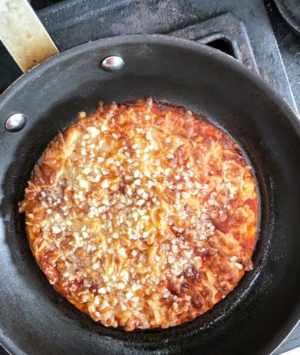 Baked pizza in a frying pan, browning the bottom crust.