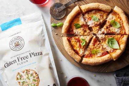 Baked gluten-free Neapolitan pizza next to bag of gluten-free pizza flour