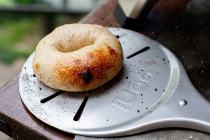 Bagel on an Ooni peel, ready to rotate and continue baking.