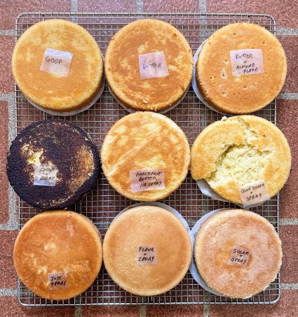 Nine round cakes on two cake racks showing the results of different types of pan prep.