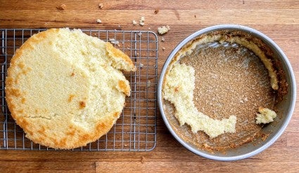 Crumbled, broken cake on a rack sitting next to the cake pan it came out of.