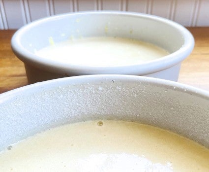 Round cake pan with batter, edges of the pan above the batter sprinkled with granulated sugar.