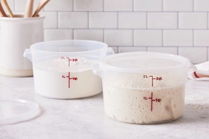 Two dough rising buckets full of proofing bread dough