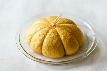 Proofed bread dough, in pie plate with string tied in the center at the top