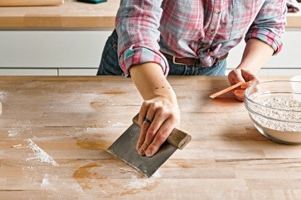 Tara using a bench knife to clean a work space 