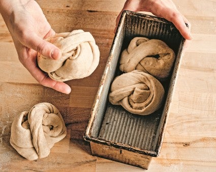 Tara putting twisted buns into a Pullman pan 