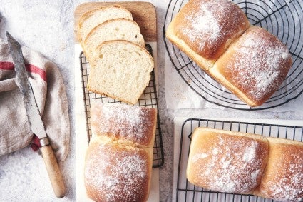 White sandwich loaves, one sliced on a bread board.