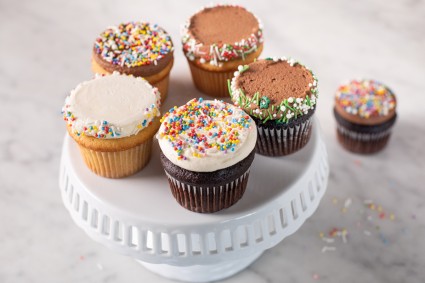 A set of flat-topped cupcakes garnished with sprinkles on a cake stand