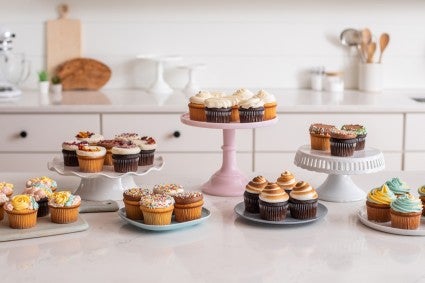 Cupcakes on different cake stands and platters decorated with a mix of designs