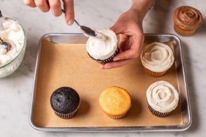 A baker decorating a cake with an offset spatula