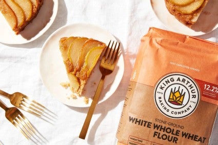 Cut maple-pear upside-down cake next to bag of white whole wheat flour