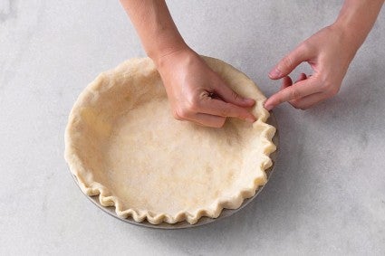 Crimping Thanksgiving pie crust in pie plate