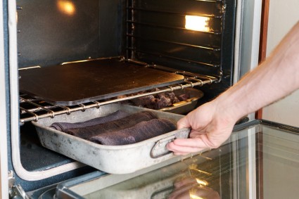 Sliding pan full of towels into oven beneath baking stone