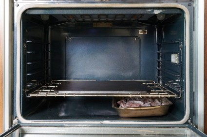 Oven with baking stone and roasting pan beneath it