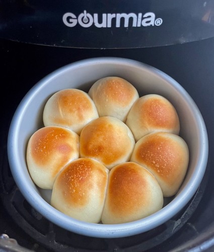 Just-baked dinner rolls in a 6" round pan in an air fryer bucket.
