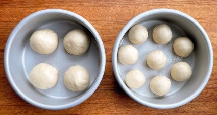 Dinner rolls rising in two 6" round pans, side by side.