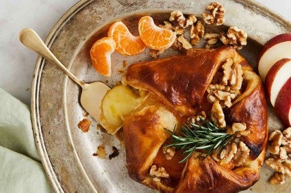 Festive plate of baked brie wrapped in puff pastry on serving plate.