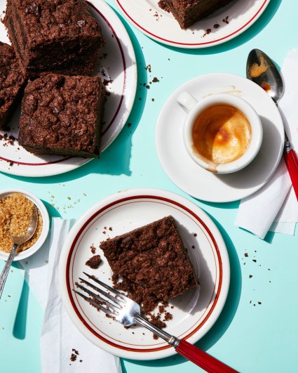 Slices of chocolate coffee cake next to coffees on a diner table