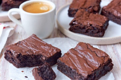 Close up of two fudge brownies and a cup of coffee.