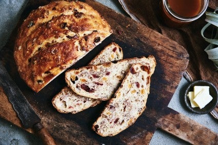 Photo of loaf of bread with a few slices cut out laying on cutting board.