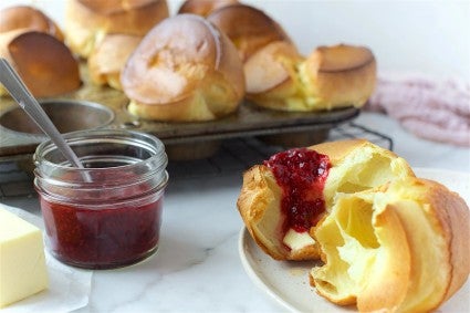 A popover torn open with jam spread on top.
