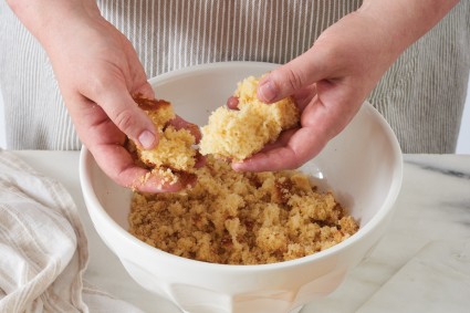 Baker using hands to break up cake into crumbles