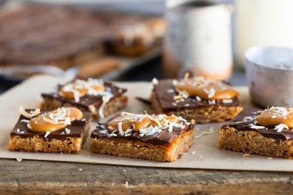 A sheet pan of coconut caramel bars topped with a layer of chocolate and toasted caramel