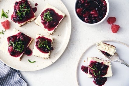 Two plates of keto-friendly cheesecake bars topped with fruit sauce