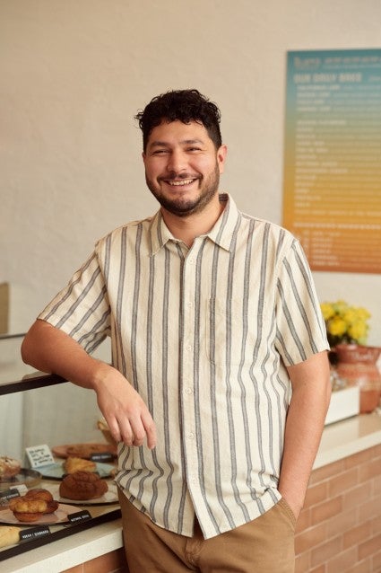 Arturo standing in front of his bakery's pastry case
