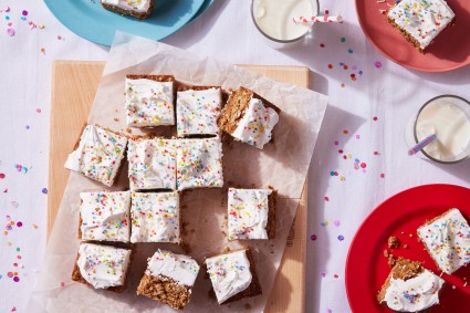 Frosted bars with sprinkles cut into pieces on a cutting board.
