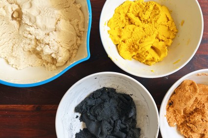 Bowls of colored masa, including black, orange, yellow, and plain