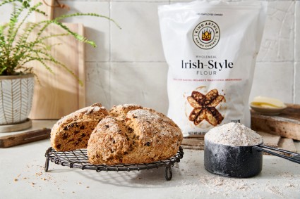 Loaf of baked bread sitting in front of a bag of Irish-Style Flour. 