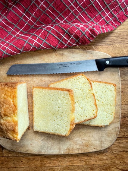 Vanilla pound cake baked in a loaf pan and sliced on a cutting board.