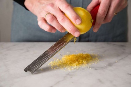 A baker zesting a lemon with a microplane