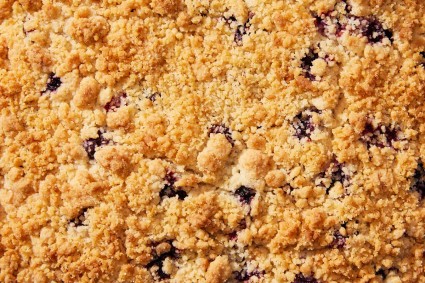 A close up shot of the golden brown crumb topping of a blueberry coffee cake