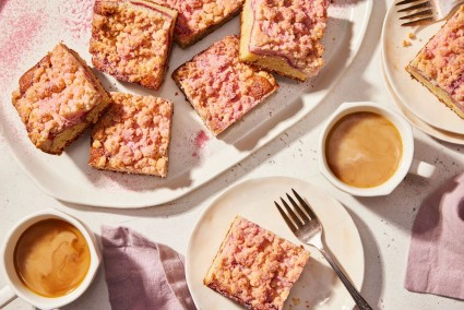 A platter of raspberry cream cheese coffee cake surrounded by cups of coffee