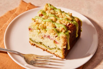 A slice of strawberry coffee cake with a stripe of green matcha filling on a plate with a fork