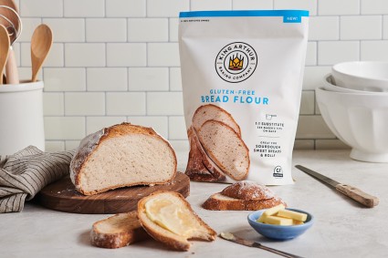 Bag of King Arthur gluten-free bread flour next to sliced loaf of artisan bread